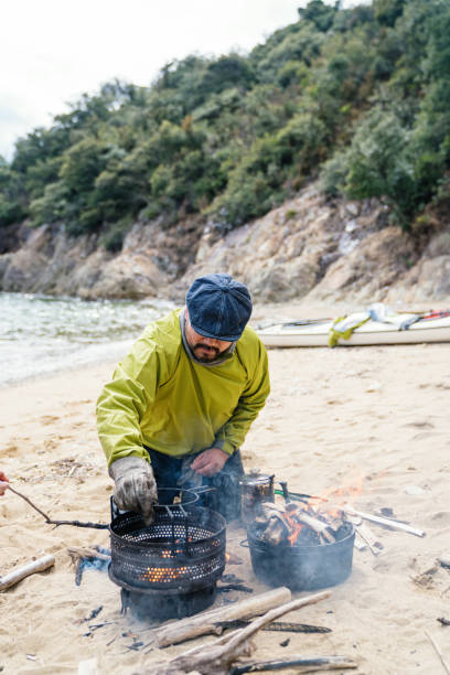 istock Man cooking and preparing lunch on a beach after sea kayaking 991125938
