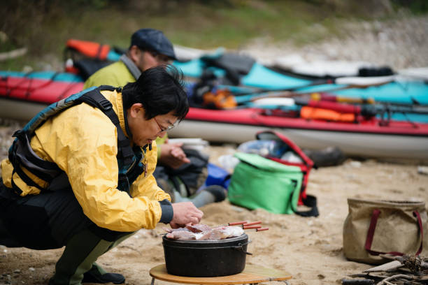 istock Man cooking and preparing lunch on a beach after sea kayaking 991128828