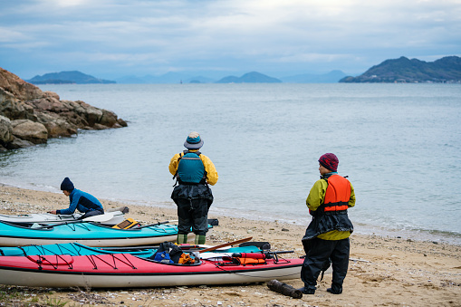 A group of men and women on a beach preparing to go sea kayaking