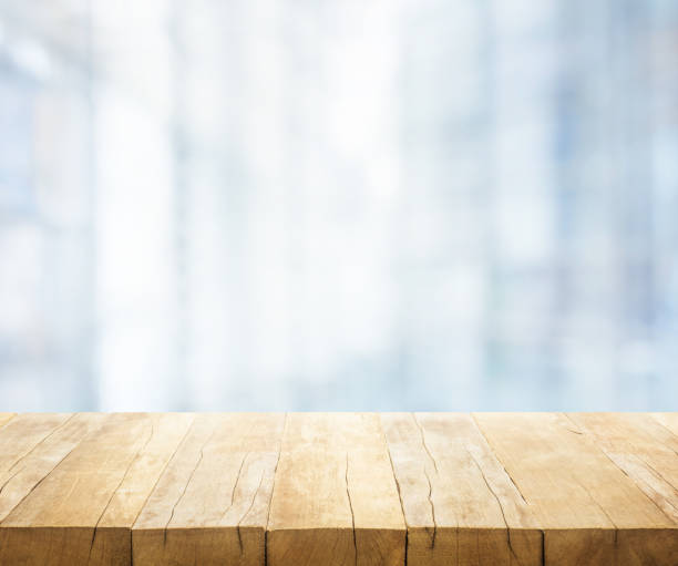 istock Wood table top on blur white glass wall background form office building 991131748