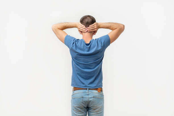 Rear view man under life crisis problems stand facing leaning against brown brick wall pounding smashing , hands raised up, wants to overcome obstacle, reach a goal, leader, motivation. Looking up.