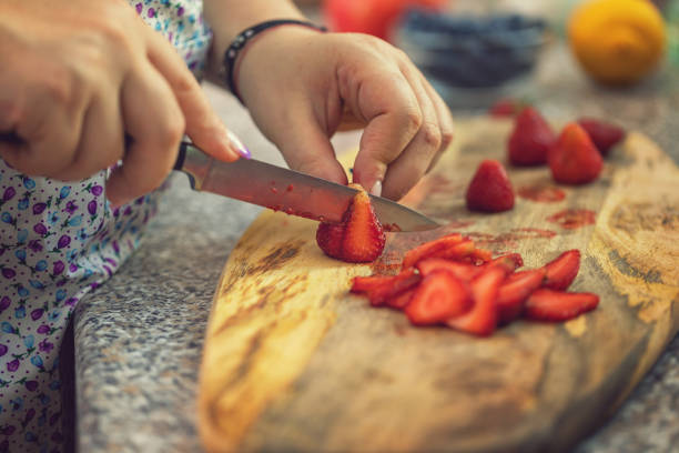 istock Young Women Cutting Fresh Strawberries 991166036