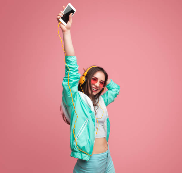 istock Young woman with smartphone dancing 991189274