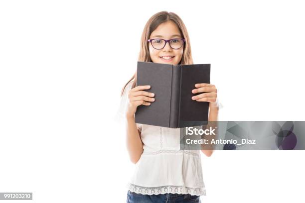 Cheerful Girl Holding A Book Looking At Camera Stock Photo - Download Image Now - Child, Book, Reading