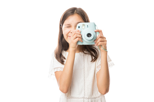Portrait on a young girl clicking photos with camera isolated on white background
