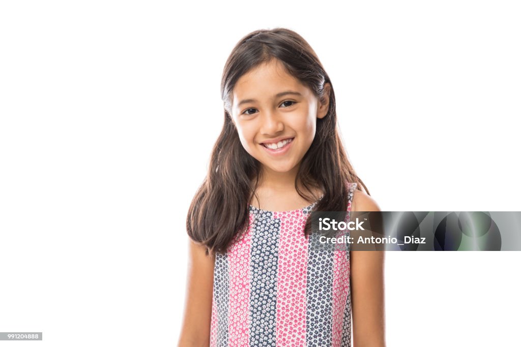 Smiling young hispanic girl posing and looking at the camera over white background Portrait of young beautiful little girl with t-shirt smiling to camera over white background Child Stock Photo