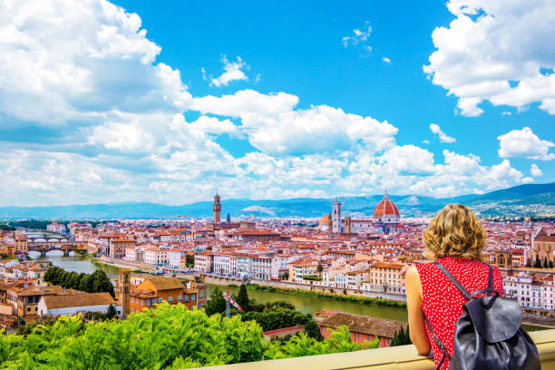 woman tourist in red admires florence firenze (duomo, arno river, towers, cathedrals, tiled roofs of houses) from piazzale michelangelo, cityscape panorama top view, florence, tuscany, italy - ponte vecchio imagens e fotografias de stock