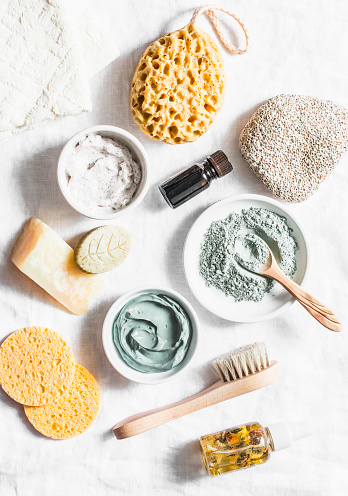Spa accessories - nut scrub, sponge, facial brush, natural soap, clay face mask, pumice stone, essential oil on a light background, top view. Healthy lifestyle concept. Beauty, skin care. flat lay