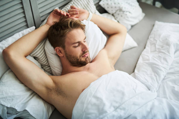 bel homme endormi dans son lit à la maison - covered nudity photos et images de collection
