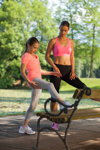 istock Mother and daughter stretching on park bench 991254478