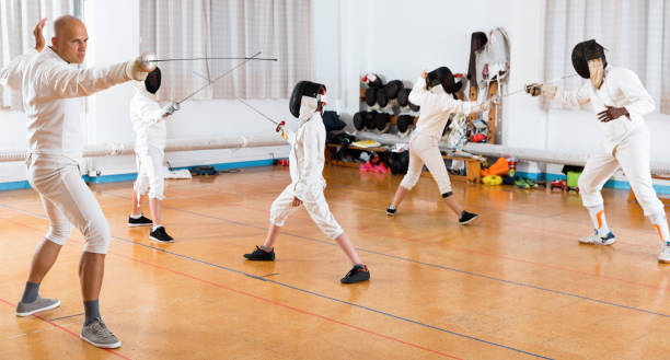 istock Coaches demonstrating to young athletes attack movements with rapier during fencing workout 991254590