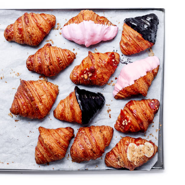 istock Croissants on a baking tray isolated on white background. Fresh various croissants with chocolate, strawberry and caramel. Top view. Collection. 991266466