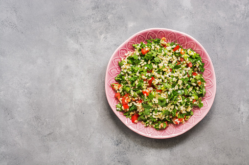 Tabbouleh salad, plate, rustic concrete background.Traditional Lebanese dish. Middle Eastern diet food. Top view, copy space