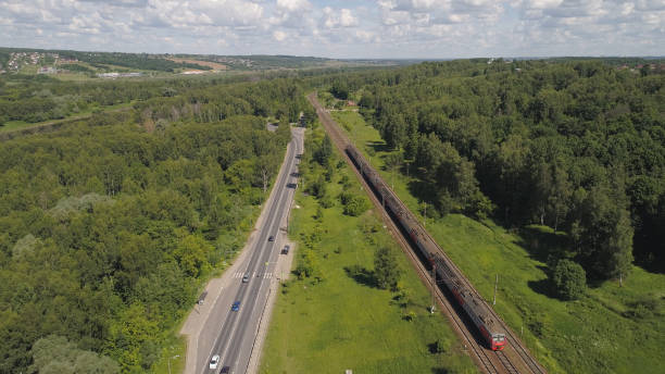 istock Highway with cars and a railway with a train 991341954