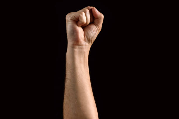 istock Male fist raised up, isolated on a dark background. Isolate 991351082