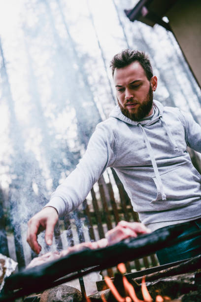 istock Handsome Male Putting Meat To Roast On Barbecue 991378728