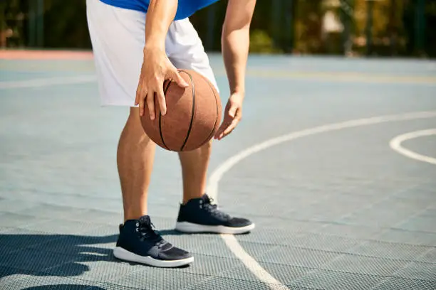 young asian male basketball player dribbling and practicing ball handling skill on court.