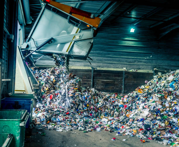 Tipping recycling into storage shed Tipping recycling into a storage shed from a refuse collection lorry. Taken with a slowish shutter speed so some of the recycling has motion blur. rubbish dump stock pictures, royalty-free photos & images