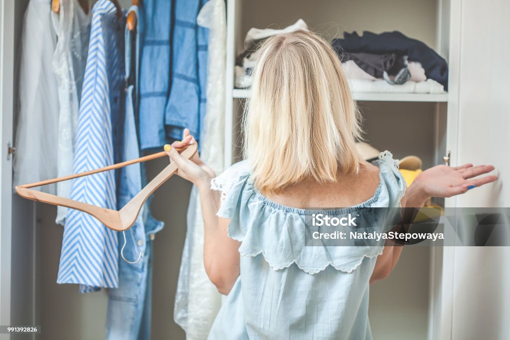 girl near a wardrobe with clothes can not choose what to wear. Heavy Choice Concept has nothing to wear girl near the wardrobe with clothes chooses what to wear Nothing To Wear Design Closet Stock Photo