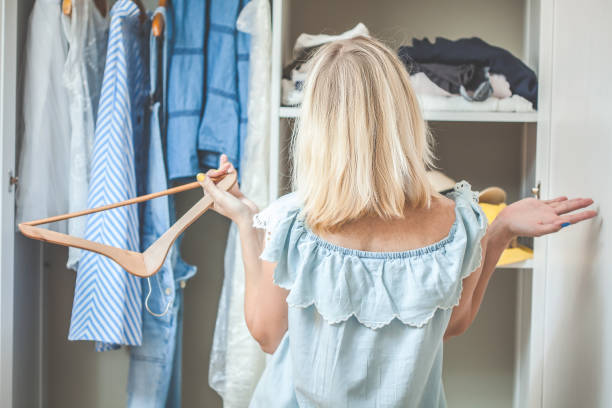 girl near a wardrobe with clothes can not choose what to wear. heavy choice concept has nothing to wear - aspirations choice choosing women imagens e fotografias de stock