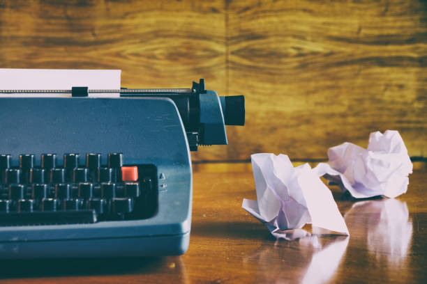 Old retro blue typewriter on a wooden desk with crumpled papers, write concept.