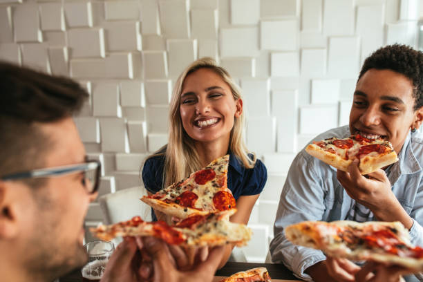 Everything's better when you do it with friends Cropped shot of a group of friends eating pizza in a bar. Selective focus. pizzeria stock pictures, royalty-free photos & images