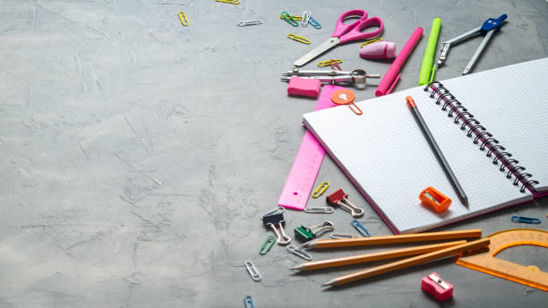 istock Preparations for school: A large white notepad, pencils, a pink ruler, scissors and other consular accessories on a gray background. 991437440