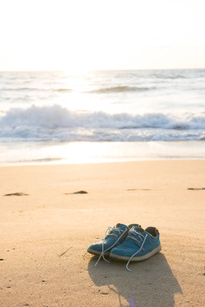 Pair of blue turquoise shoes on the beach at sunset or sunrise
