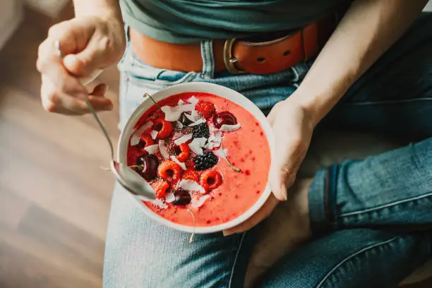 Young woman eating healthy detox smoothie bowl with berries. View from above. Lifestyle. Healthy detox weight loss concept
