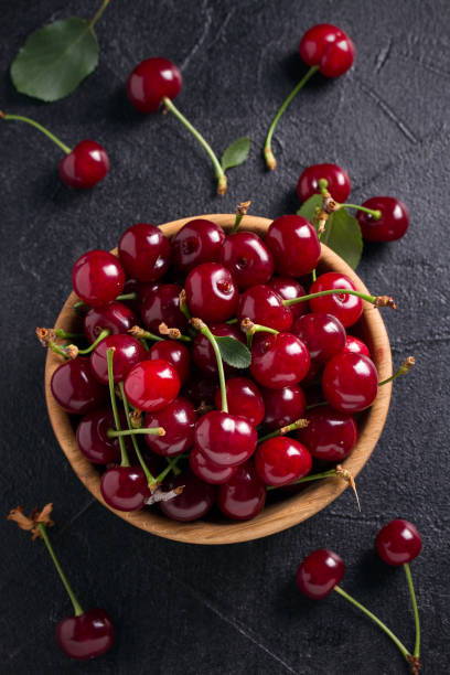 istock Fresh cherry in wooden bowl on black background 991439268