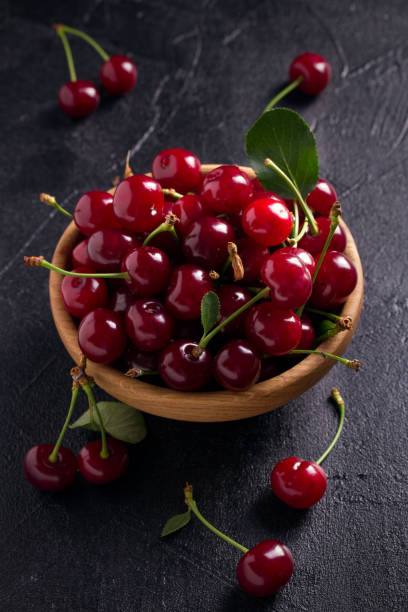 istock Fresh cherry in wooden bowl on black background 991443074
