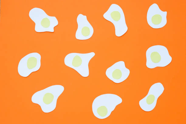 istock Many friend eggs prepared sunny side up cut from paper placed on orange background 991510094