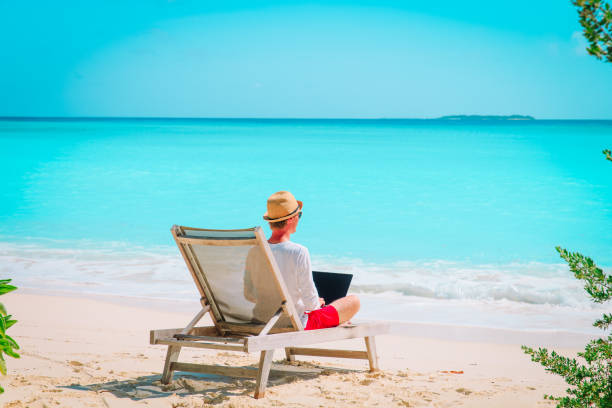 istock young man working on laptop at beach 991600728
