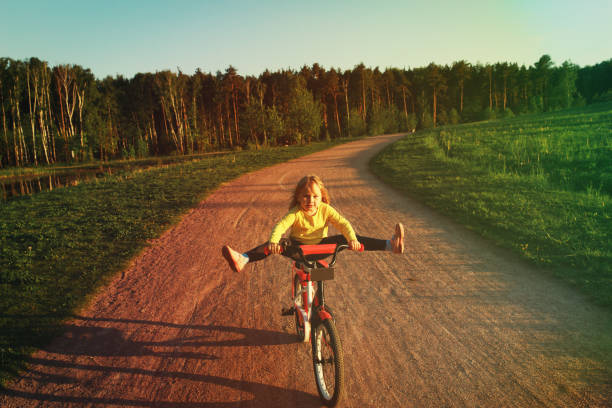 little girl doing tricks riding bike in summer nature, kids sport