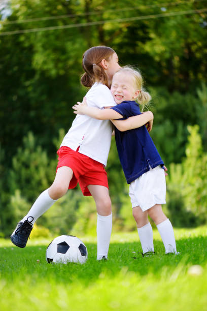 istock Two cute little sisters having fun playing a soccer game 991613764