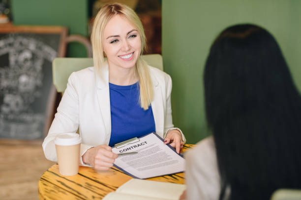 istock Happy confident attractive young female manager explaining contract conditions and showing it to customer during meeting in cafe 991660506