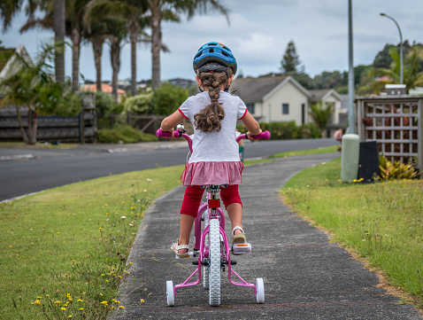 Little girl learning to ride a bike outside