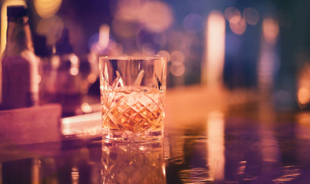 Whiskey on the rocks served in vintage glass at bar Whiskey with ice served in vintage glass on bar counter at night brandy photos stock pictures, royalty-free photos & images