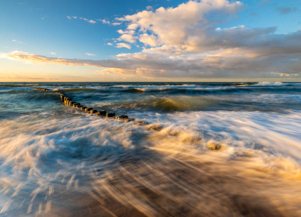 istock sunset over the sea beach in Poland, waves dynamically breaking into the beach 991791542