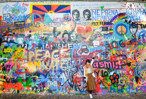 Prague, Czech Republic - October 11, 2017: The Lennon Wall or John Lennon Wall, Prague Czech Republic. Since the 1980s it has been symbol of global ideals such as love and peace. Girls making photos in front of Lennon Wall