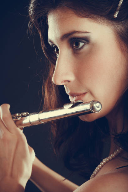 istock Woman playing transverse flute on black. 991798560