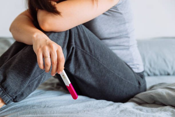 istock sad woman on bed with negative pregnancy test 991803978