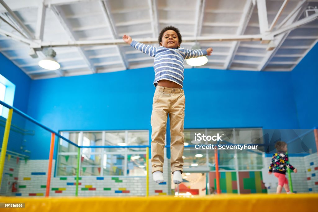 Chico afroamericano disfrutar de camas elásticas - Foto de stock de Trampolín - Artículos deportivos libre de derechos