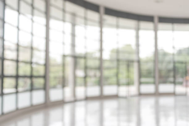 istock Blur background interior view looking out toward to empty office lobby and entrance doors and glass curtain wall 991820088