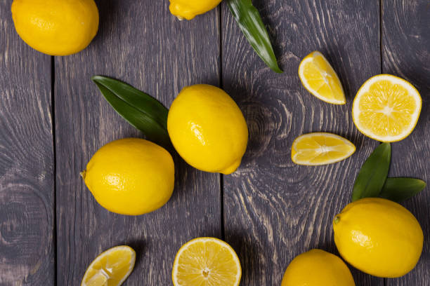 istock Large yellow lemons and pieces are scattered on wooden surface 991838366