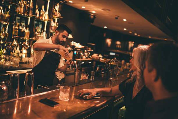 bartender making cocktails at retro bar for mature couple - retro revival couple men elegance imagens e fotografias de stock