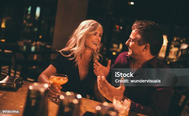 Senior Husband And Wife Laughing And Having Drinks At Bar Stock Photo - Download Image Now