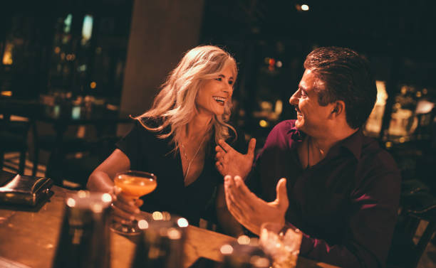 senior husband and wife laughing and having drinks at bar - retro revival couple men elegance imagens e fotografias de stock