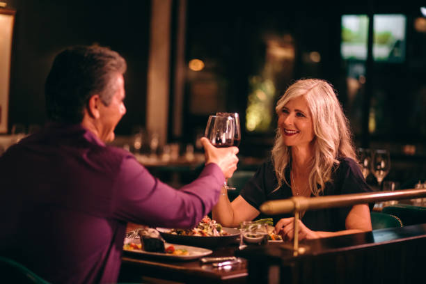 Smiling mature husband and wife toasting with wine at dinner Senior couple in love toasting with red wine and having dinner at fine dining restaurant old rich white guy stock pictures, royalty-free photos & images