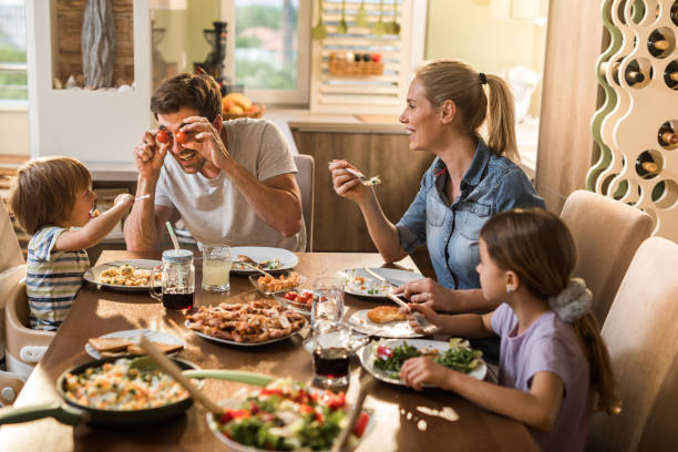 Playful father entertaining his family during lunch at dining table.